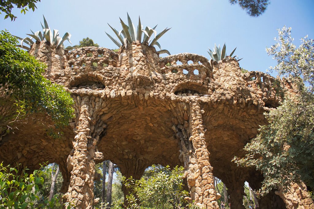 Stone viaduct structures designed by Gaudí inside Park Güell in Barcelona surrounded by trees