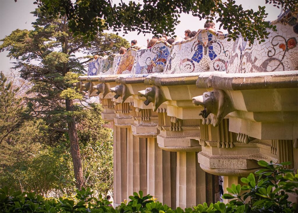 Visitors walking around the monumental area of Park Güell with columns and terraces in Barcelona