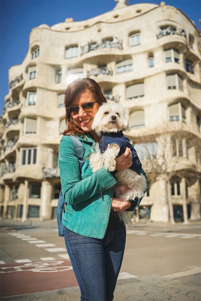 Traveler holding a small dog near Casa Milà in Barcelona, representing Wander Woofs pet-friendly travel services in Spain.